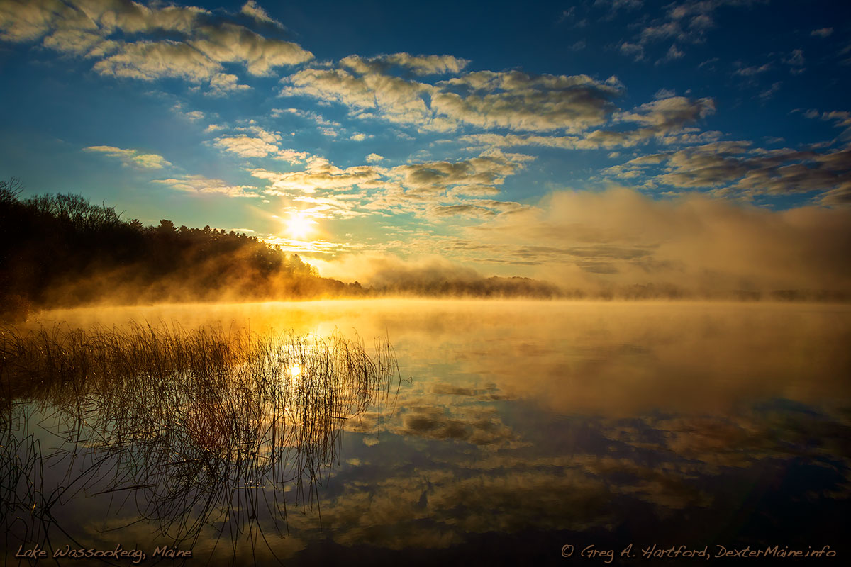 Thick fog at sunrise on Lake Wassookeag with blue sky and clouds