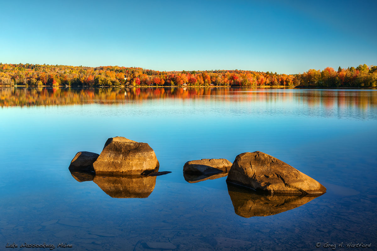 The large boulders create an interesting composition with the multi-colored autumn leaves and reflections on the surface of the very calm water.