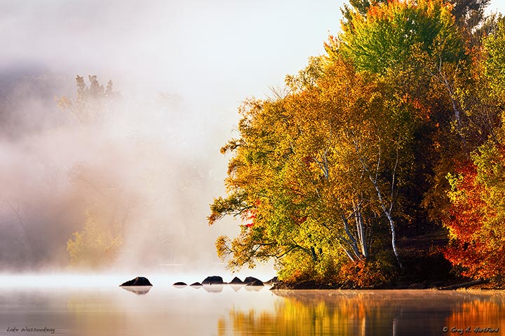 Autumn sunrise on Little Lake Wassookeag during mid October with a dense fog